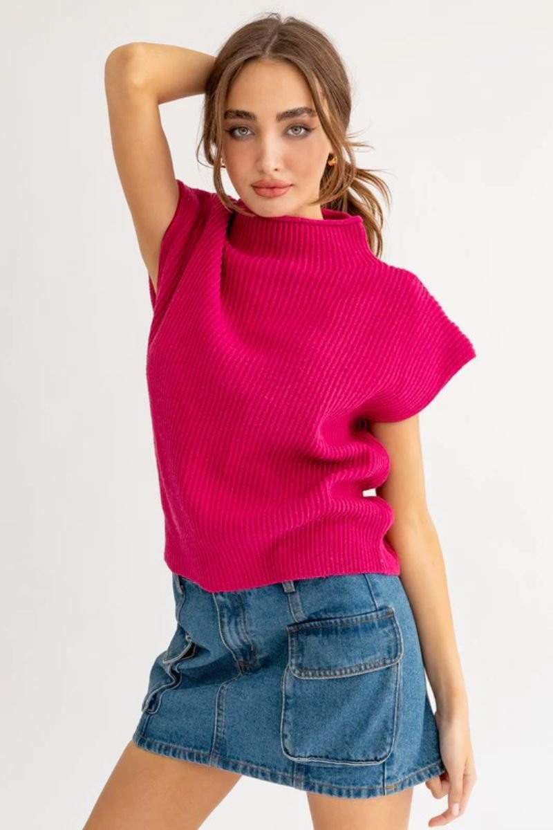 The model is wearing a fuchsia sweater with short sleeves, along with a jean skirt.