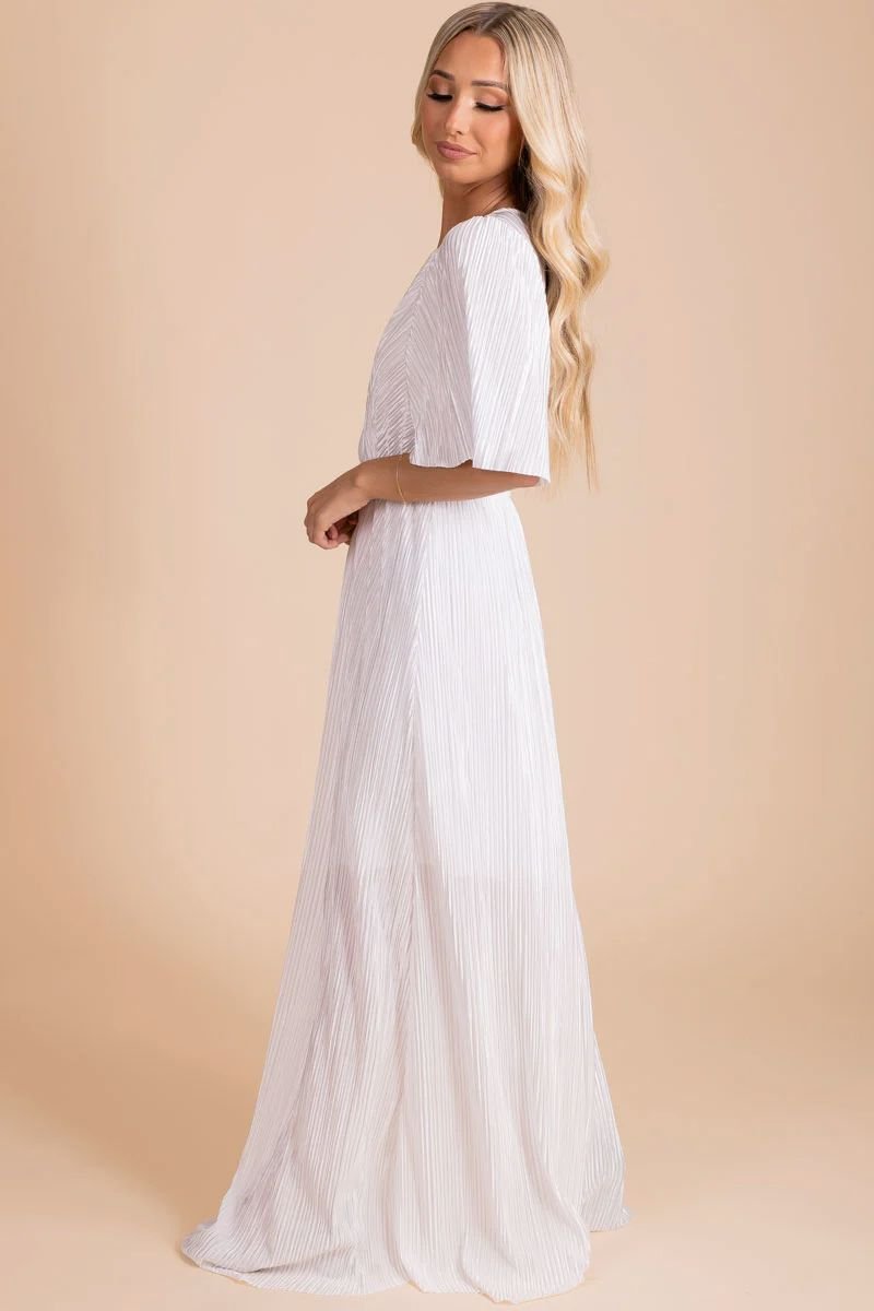 Clair de Lune Maxi Dress. The model is wearing a floor length white dress with elbow length sleeves and the fabric is ribbed material.