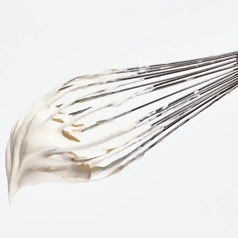 Silver whisk with thick whipped cream falling off the end. 