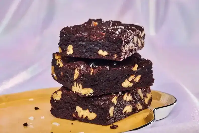 Brownies made with weed butter and chopped walnuts, covered in flaky salt.