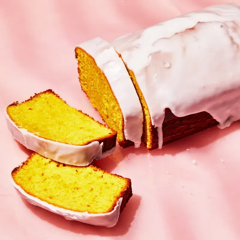 Glazed lemon loaf cake on a pink surface.
