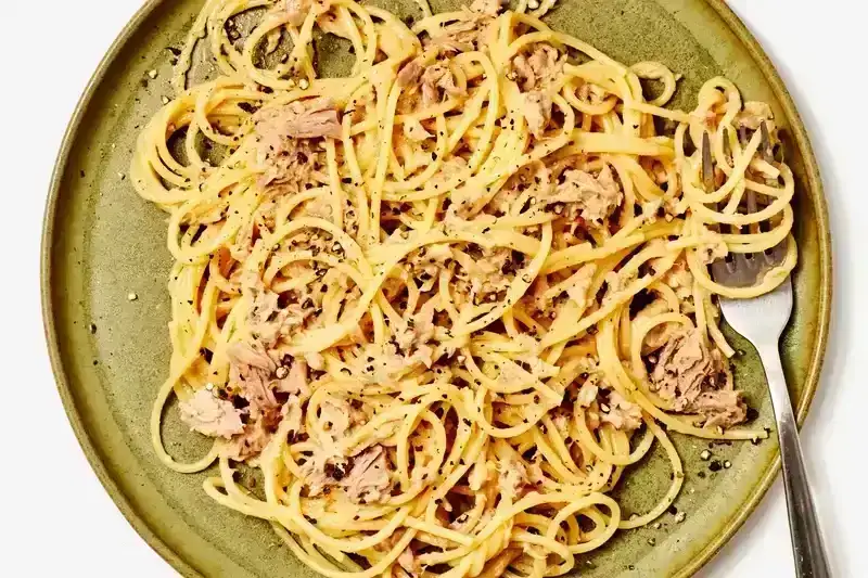 Tuna Spaghetti on a green plate with a fork in it.