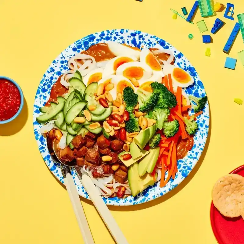 a mix of brocolli, eggs, nuts, and other veggies on a blue paint splattered plate
