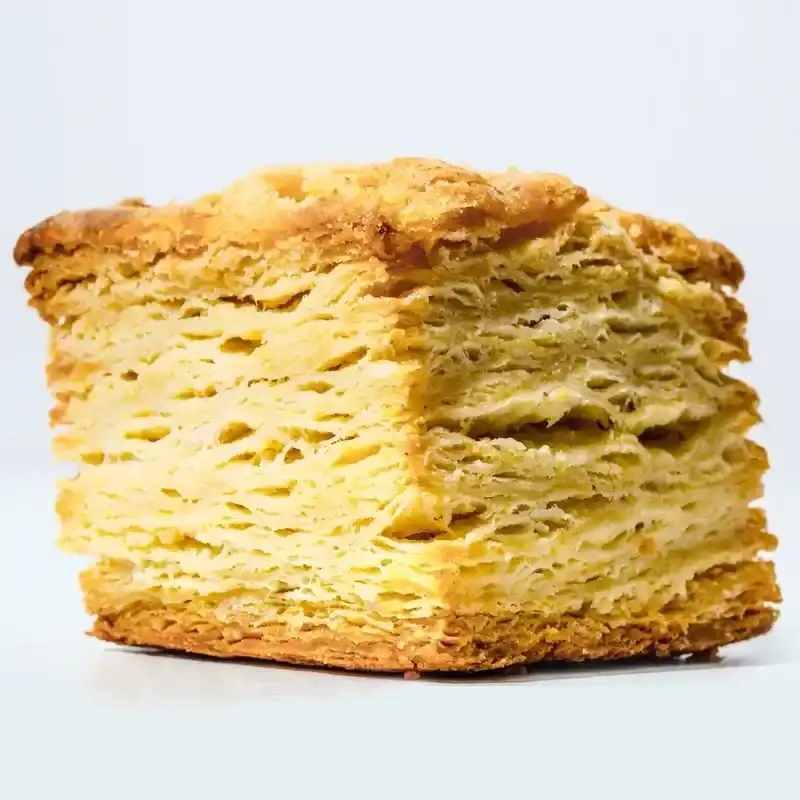 A single tall laminated buttermilk biscuit as seen from the side.