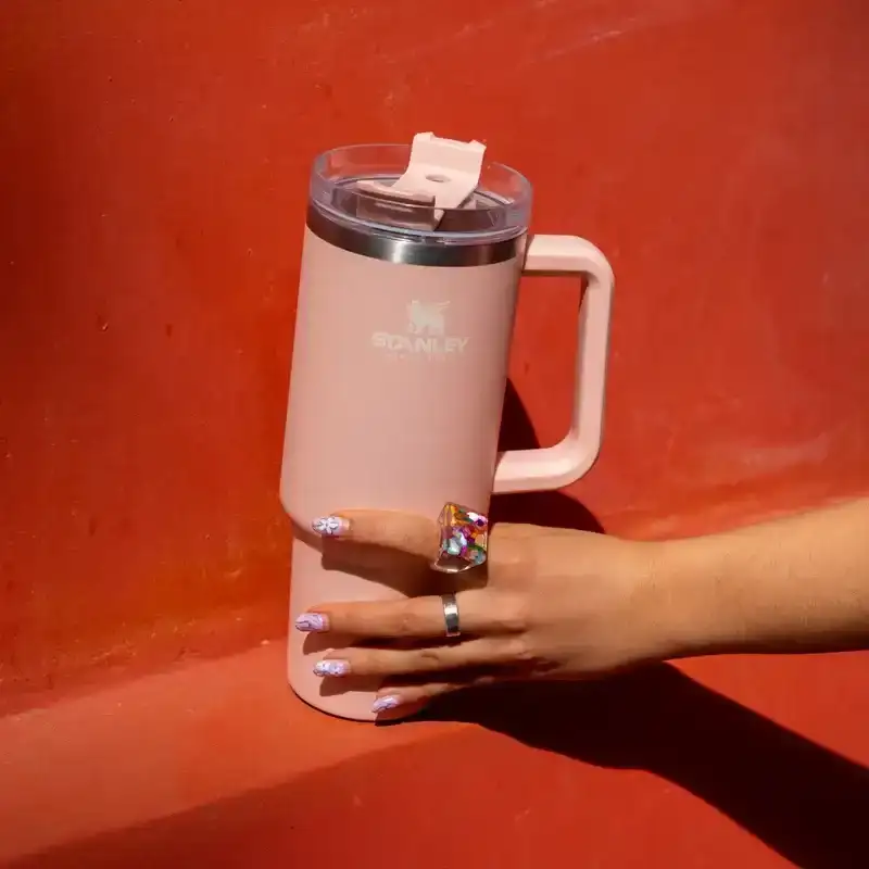 The Pink Adventure Quencher Travel Tumbler on a red wall, from Stanley, May 12, 2022. 