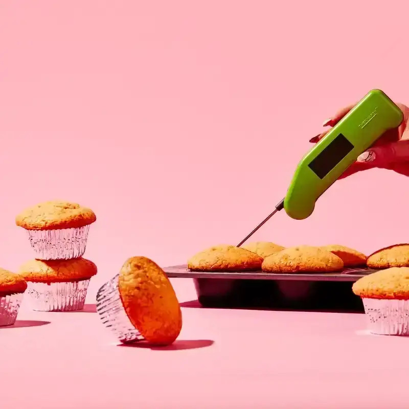A Thermapen being put into a orange muffin in a muffin tin