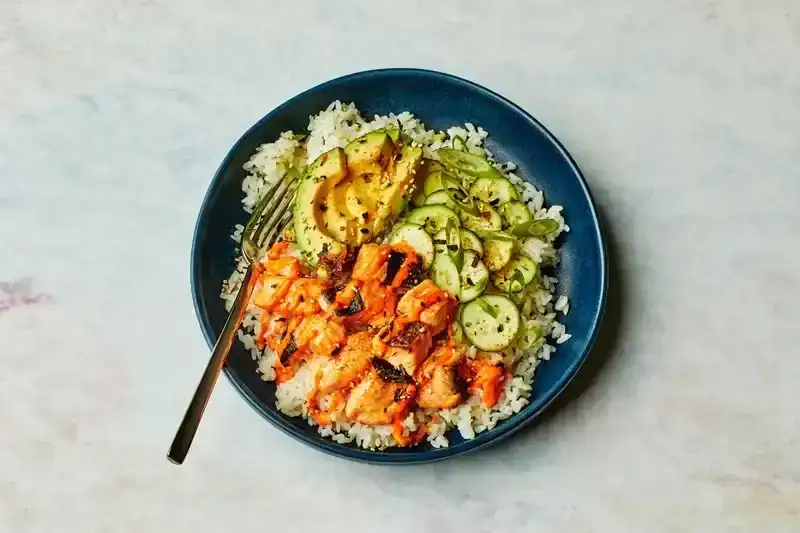 A blue bowl with salmon, rice, and avocado