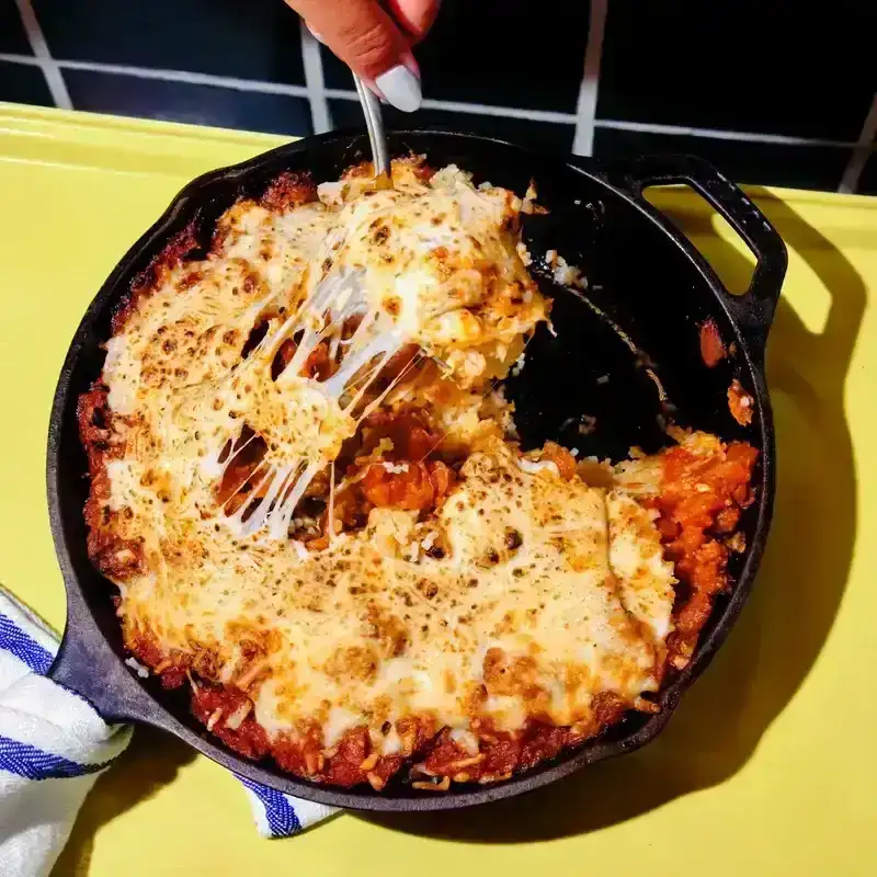 A skillet filled with Cheesy Pork Chop Rice on a yellow surface