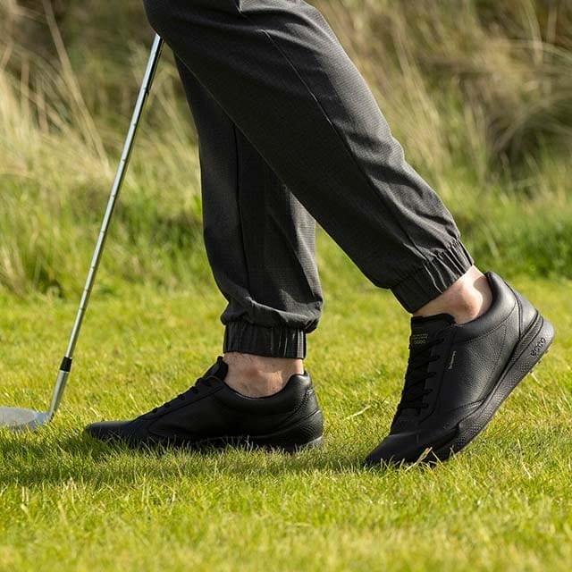 Golfer on course wearing black hybrid golf shoes