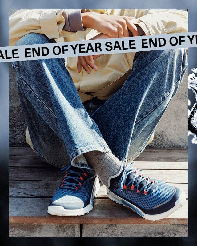 Man sitting on wooden bench wearing blue outdoor sneakers