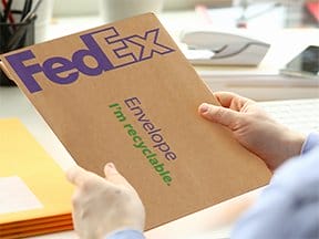 Someone holds a FedEx Office package ready to ship.