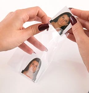 Hands holding freshly cut visa photos.