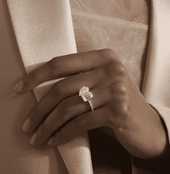 A hand is seen wearing a beautiful diamond ring.