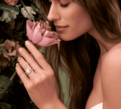 Romantic background with flowers where female model is wearing a diamond engagement ring with matching band.