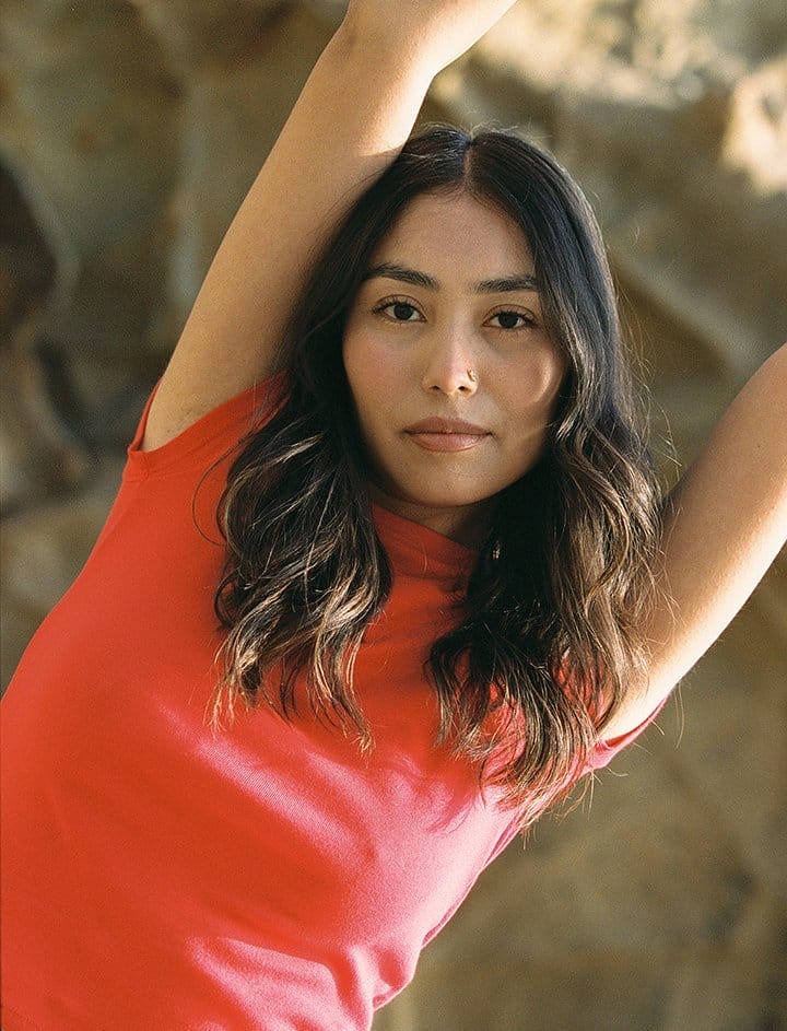 close up shot of brunette woman wearing red tee shirt and lifting up her arms out of frame.