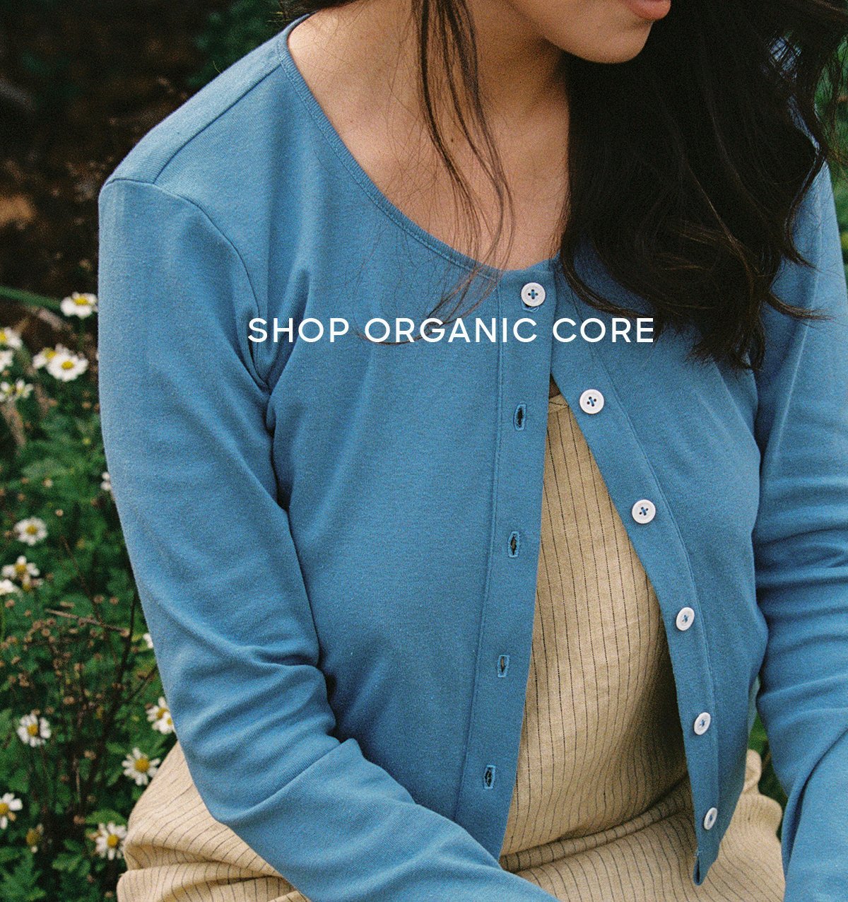 closeup of blue cardi worn over pale yellow dress in a garden on model