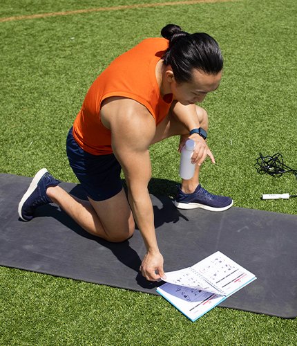 Man outside on a yoga mat flipping through guide