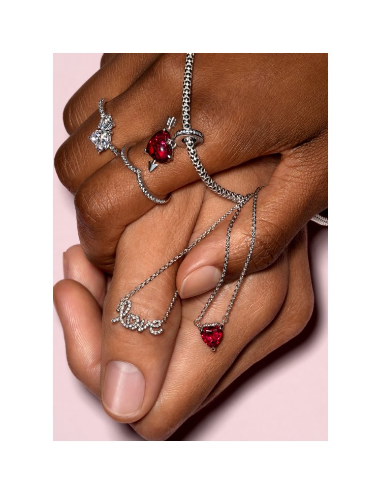 Two hands wearing and holding pandora jewelry
