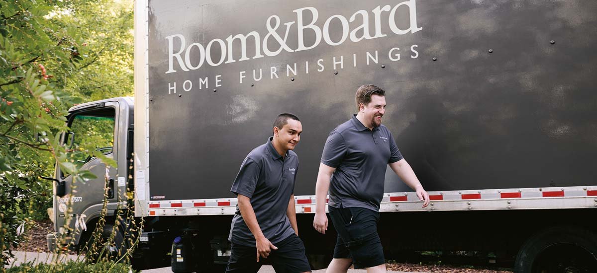 Room & Board delivery truck with two employees walking in front of it
