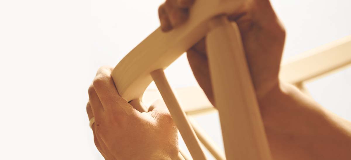 Closeup of a craftspersons's hands putting together a chair