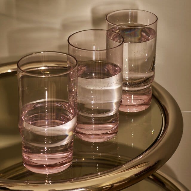 Three glasses of water on a glass and chrome table containing different levels of water.