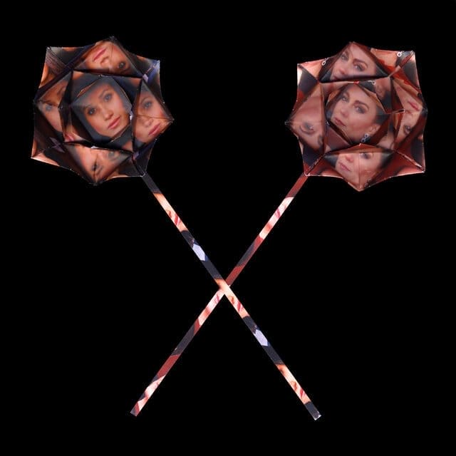 Two origami roses with their stems crossed, forming an X. The roses bear the faces of Kate Middleton and Meghan Markle.
