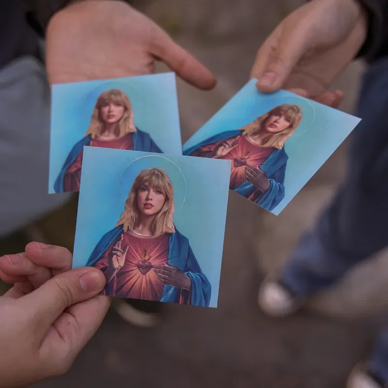 People holding cards depicting Taylor Swift as Jesus 