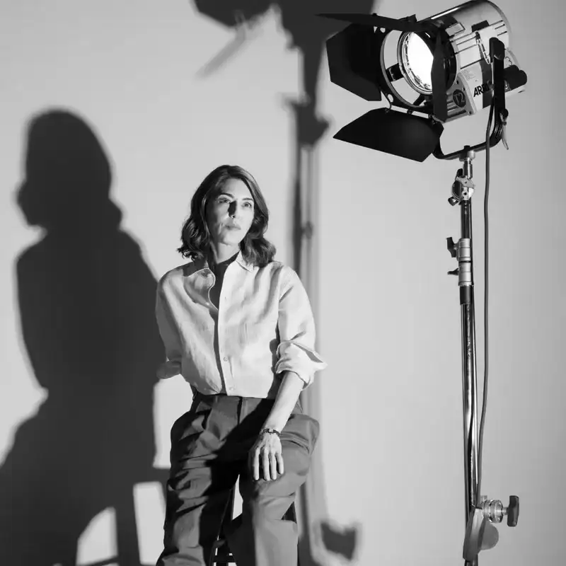 Sophia Coppola sits on a stool under a bright light. 