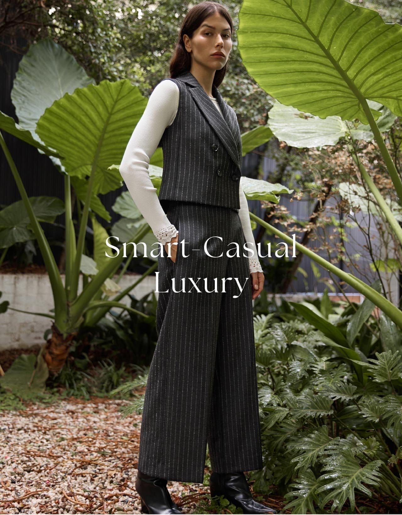 The model is wearing Wool Pinstripe Waist Coat layered with Long Sleeve Lace Trim Knit and paired with Wool Pinstripe Crop Pant